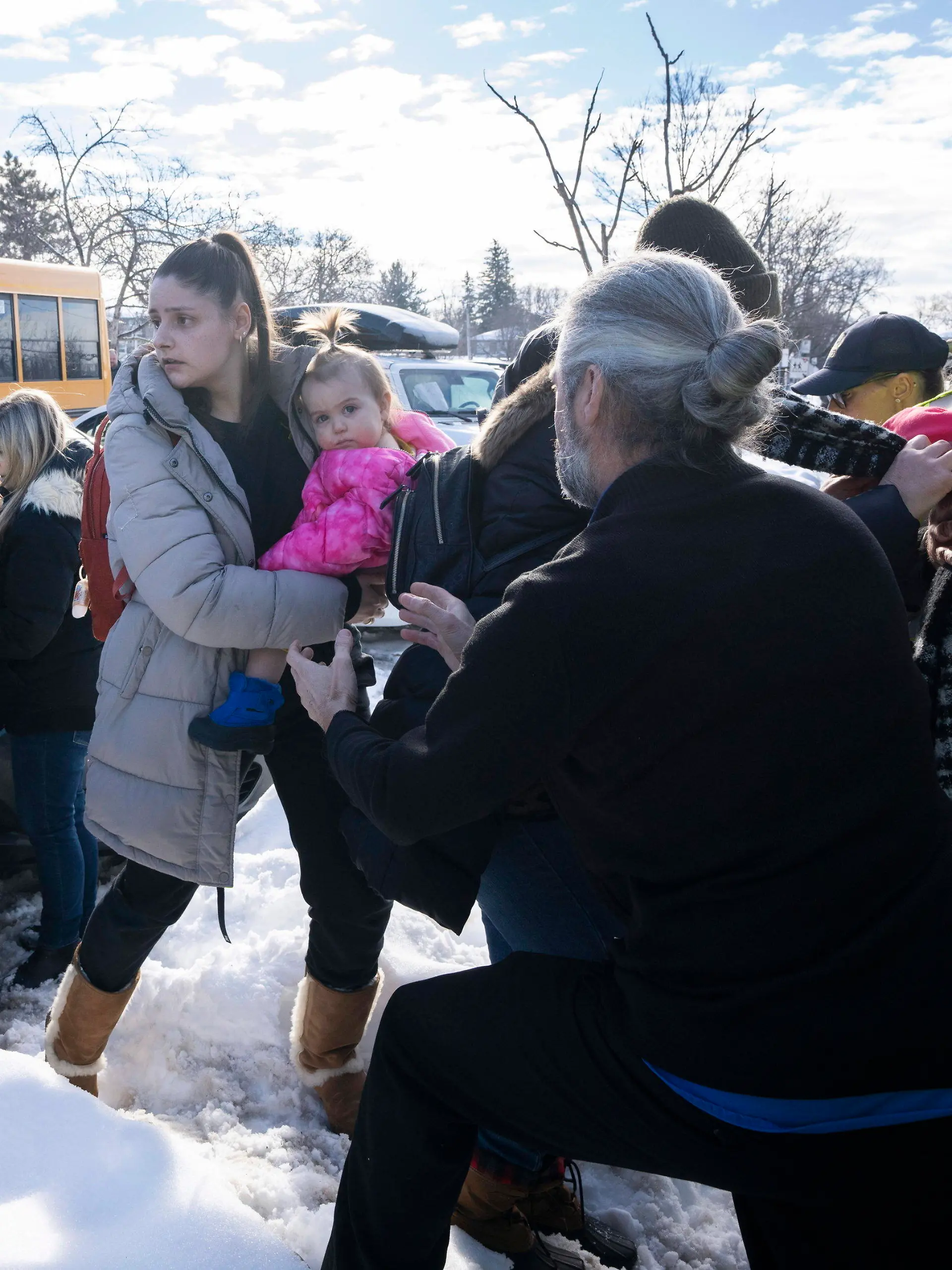 Parents and their children are loaded onto a warming bus as they wait for news after a bus crashed into a daycare centre in Laval, Quebec, on Wednesday, Feb. 8, 2023. (Ryan Remiorz/The Canadian Press via AP)