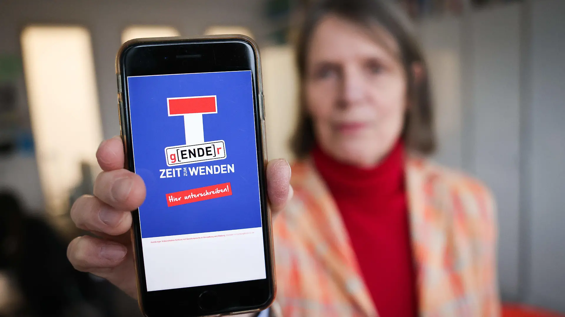03.02.2023, Hamburg: Sabine Mertens, Bundesvorstand im Verein Deutsche Sprache, hält ihr Smartphone mit einem Plakatentwurf einer Volksinitiative gegen die Gendersprache in Verwaltung und Bildung. (zu dpa «Initiatoren wollen Hamburger Volksinitiative gegen Gendern anmelden») Foto: Christian Charisius/dpa - ACHTUNG: Nur zur redaktionellen Verwendung im Zusammenhang mit der aktuellen Berichterstattung +++ dpa-Bildfunk +++