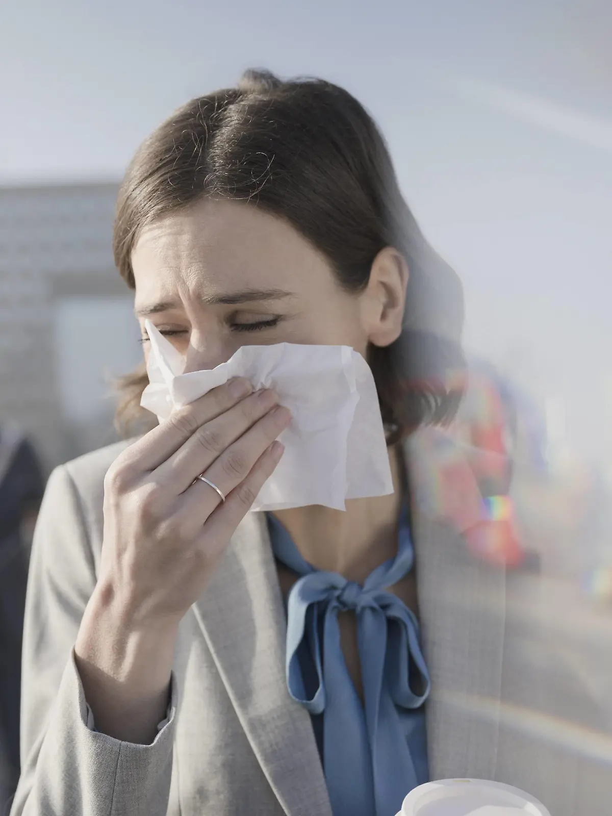 Businesswoman blowing nose into tissue Businesswoman with allergies blowing nose into tissue on sunny urban sidewalk PUBLICATIONxINxGERxSUIxHUNxONLY CAIAxIMAGE/SCIENCExPHOTOxLIBRARY F019/3106  