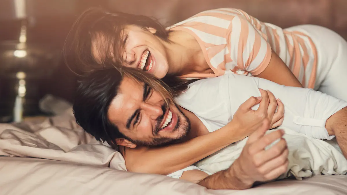 Happy young playful couple in bed.