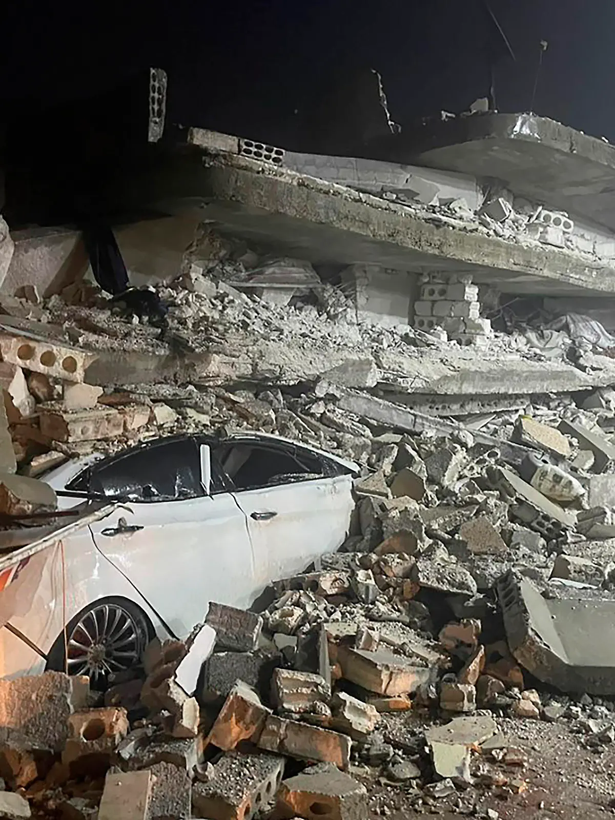 06.02.2023, Syrien, Azmarin: Ein Auto ist unter den Trümmern eines eingestürzten Gebäudes in der Stadt Azmarin in der nordsyrischen Provinz Idlib zu sehen. Zwei heftige Erdbeben haben kurz nacheinander am frühen Montagmorgen den Südosten der Türkei erschüttert. Das Epizentrum lag nach Angaben des Geoforschungszentrums Potsdam in beiden Fällen nahe der Stadt Gaziantep unweit der Grenze zu Syrien. Demnach ereigneten sich die Beben gegen 4.17 Uhr (Ortszeit/2.17 Uhr MEZ) und 4.28 Uhr (Ortszeit/2.28 Uhr MEZ) in einer Tiefe von 10 Kilometern. Foto: Ghaith Alsayed/AP/dpa +++ dpa-Bildfunk +++