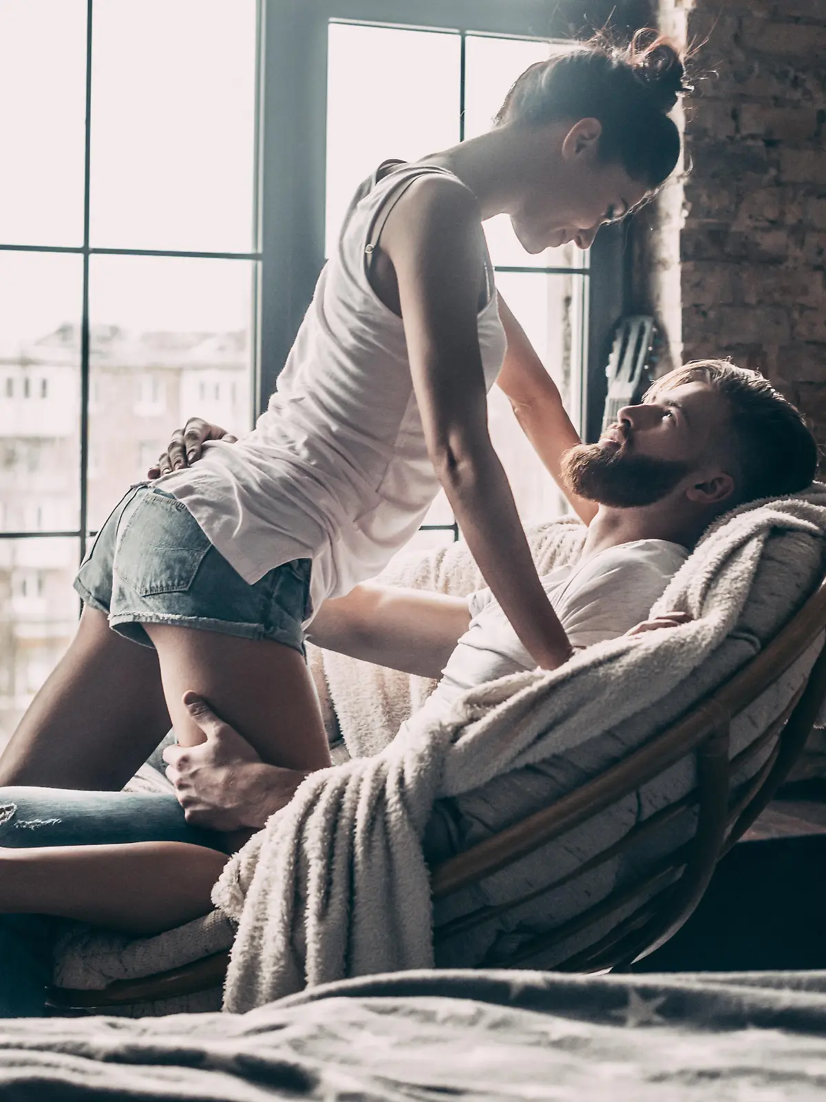 Young passionate couple looking on each other while spending free time at home