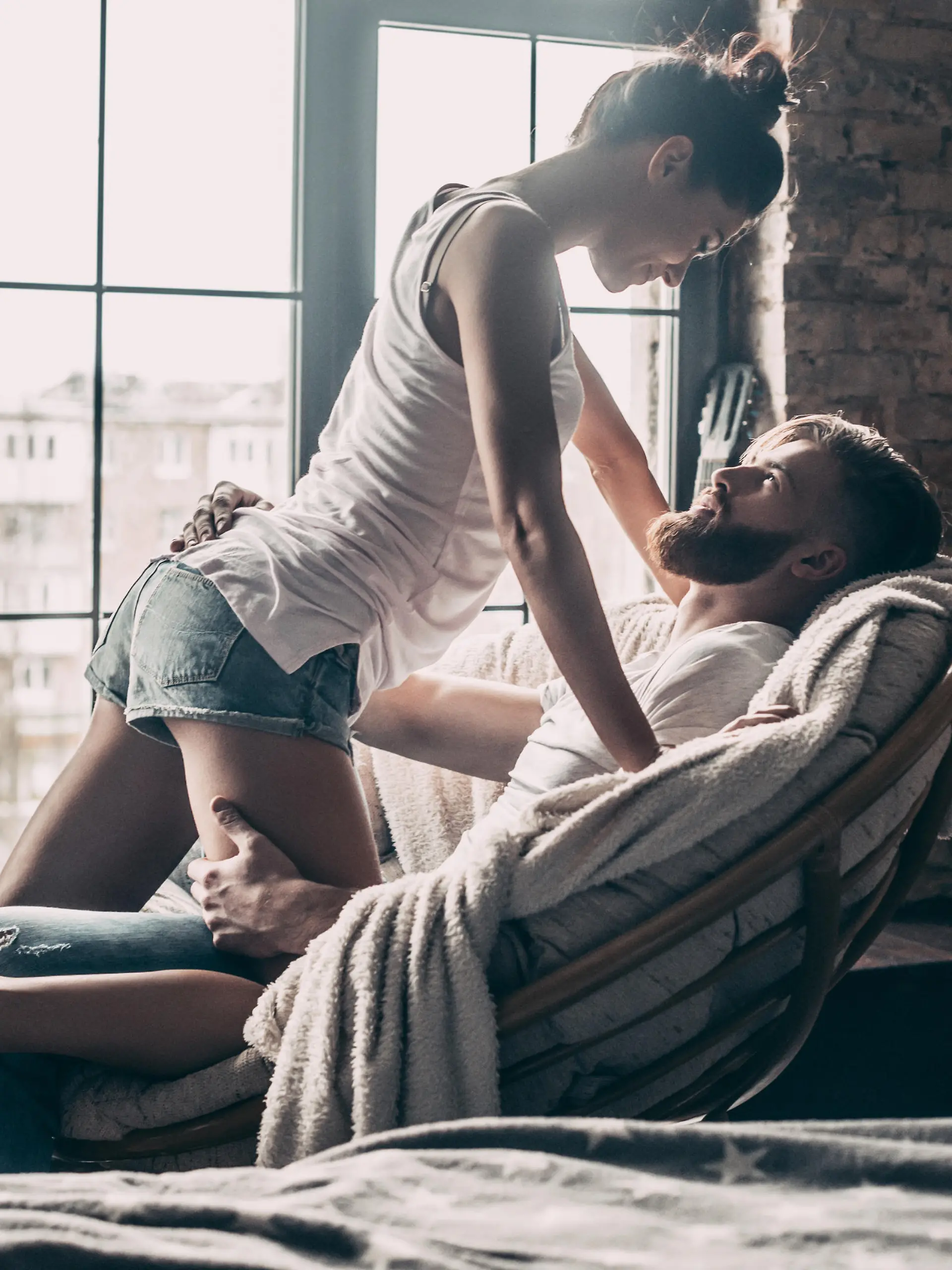 Young passionate couple looking on each other while spending free time at home