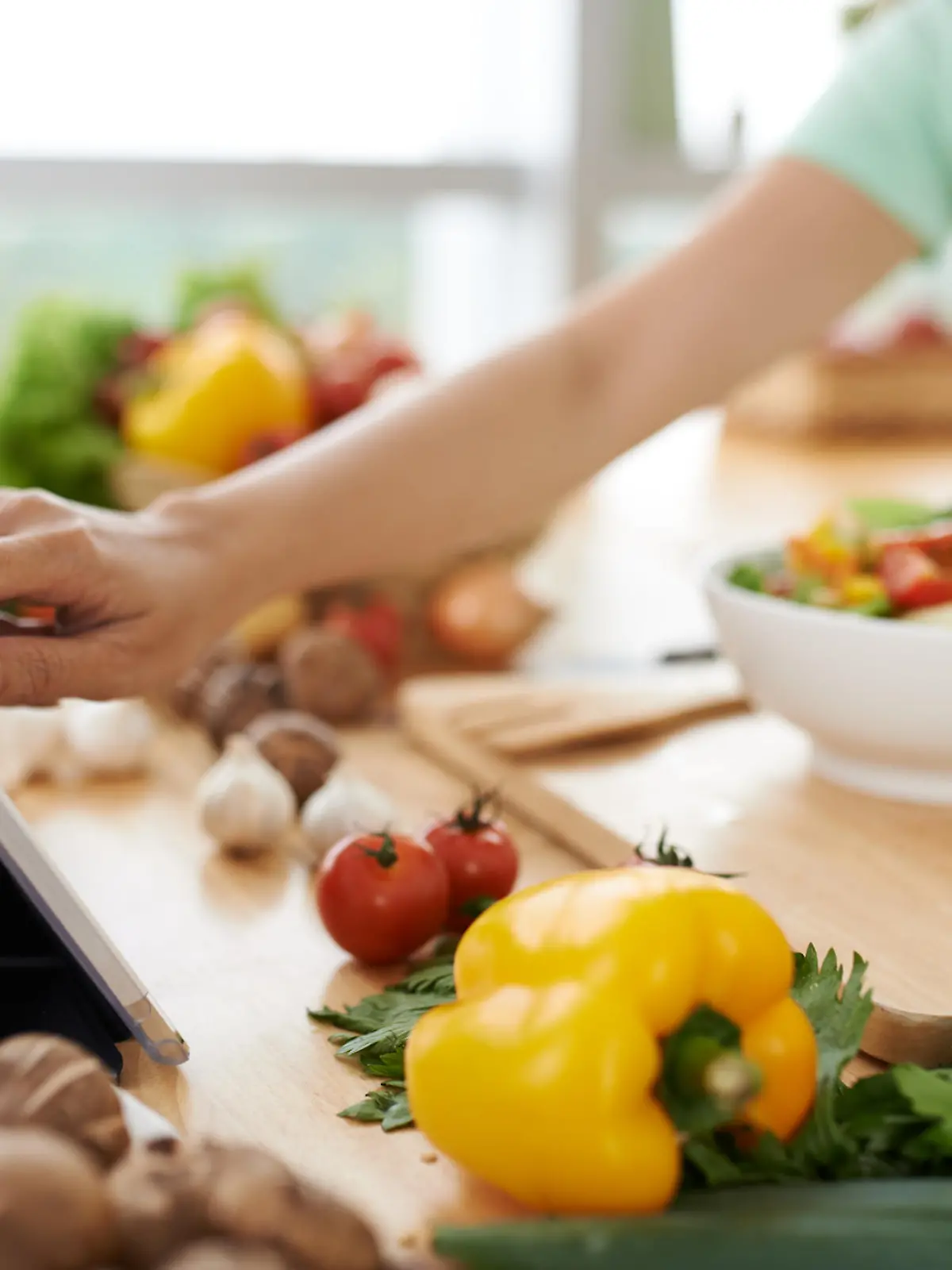 Woman checking recipe on digital tablet before seasoning salad