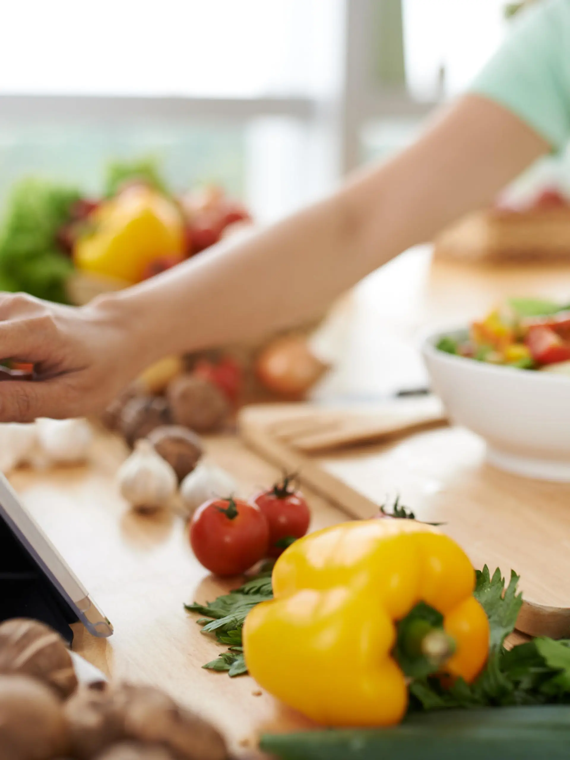 Woman checking recipe on digital tablet before seasoning salad