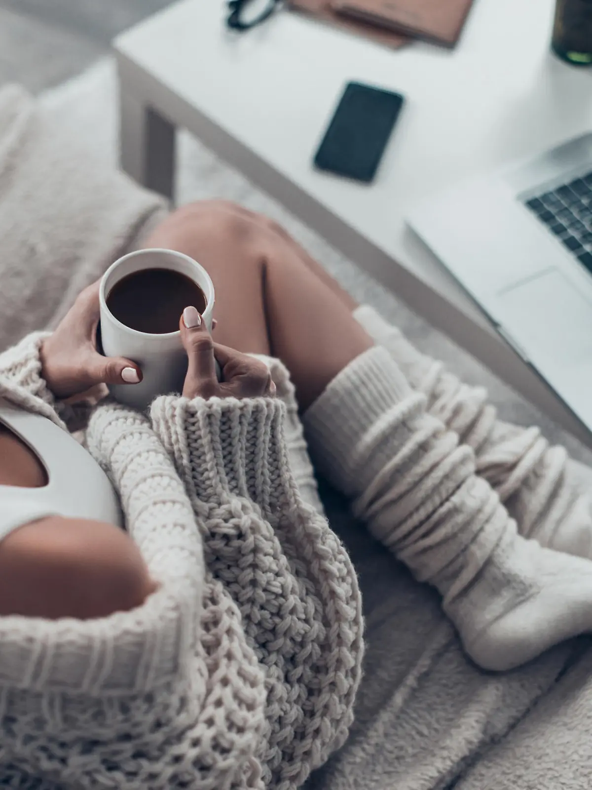 Top view of attractive young woman holding cup while relaxing on couch at home