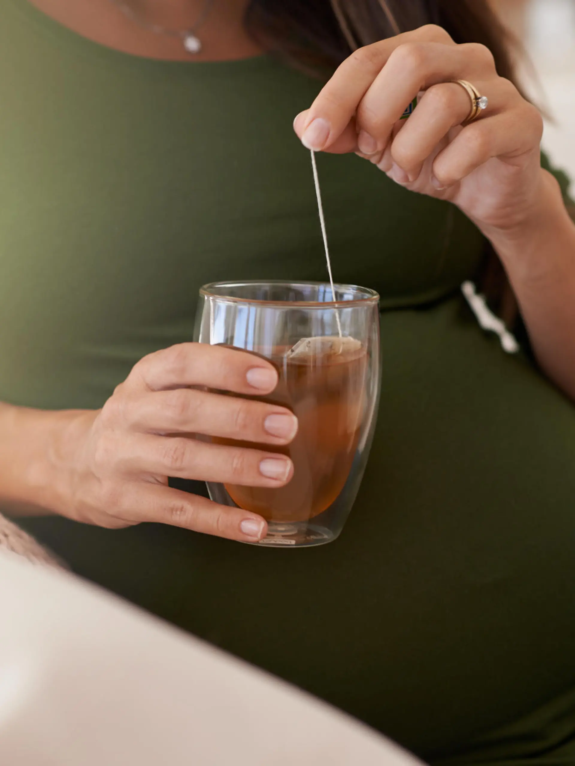 Closeup shot of a pregnant woman relaxing at home with a glass of tea