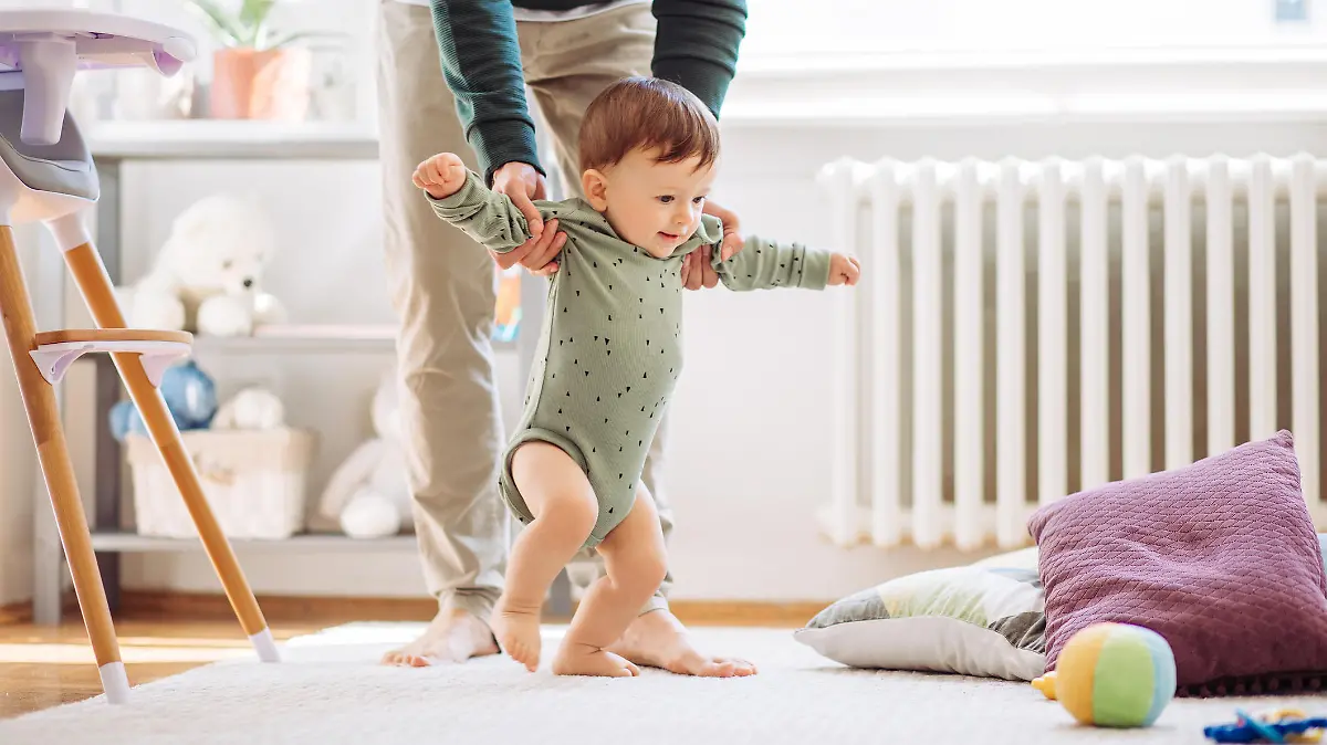 Babys erste Schritte: kleiner Junge lernt laufen