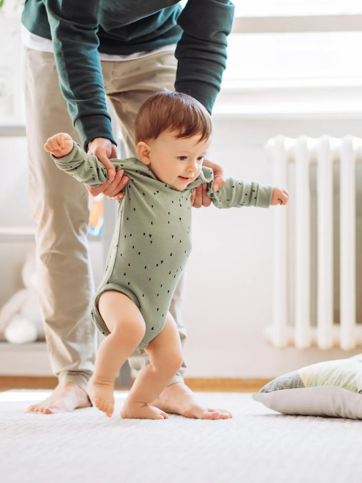 Babys erste Schritte: kleiner Junge lernt laufen
