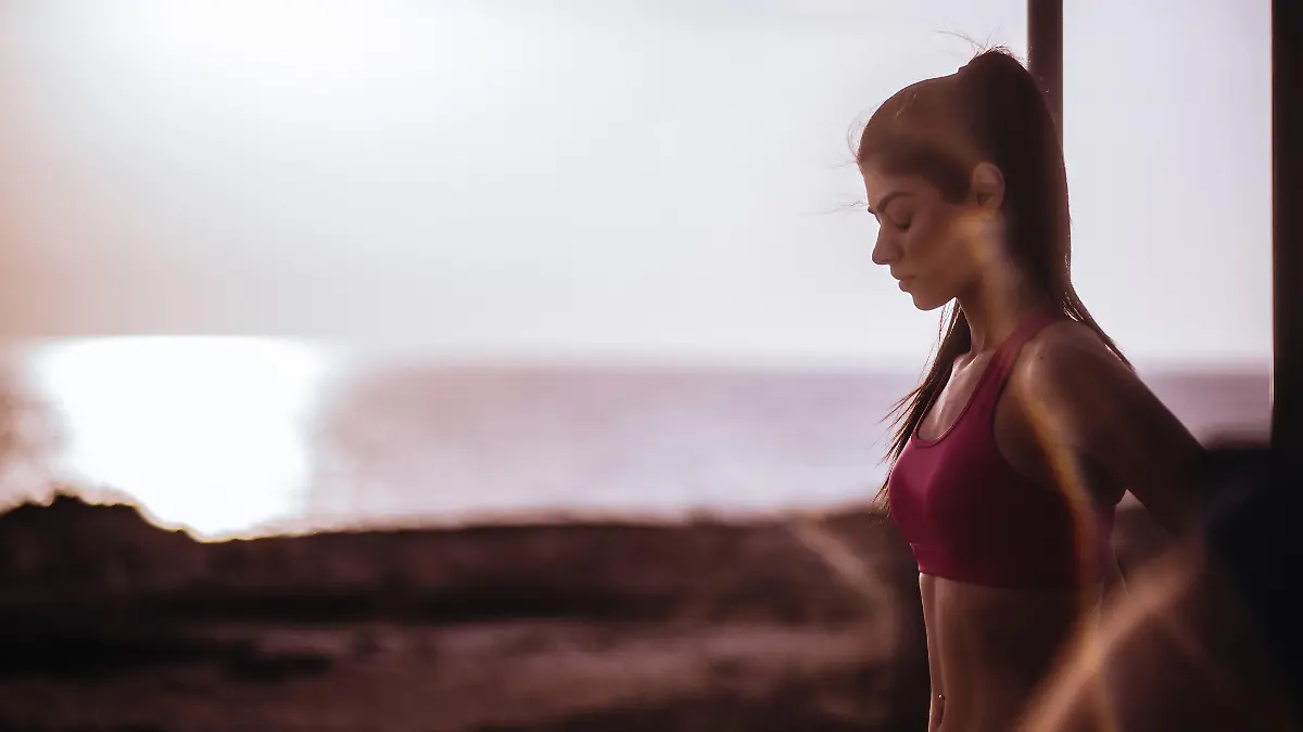 Atractive female fitness model having a break during workout at sunset next to the sea