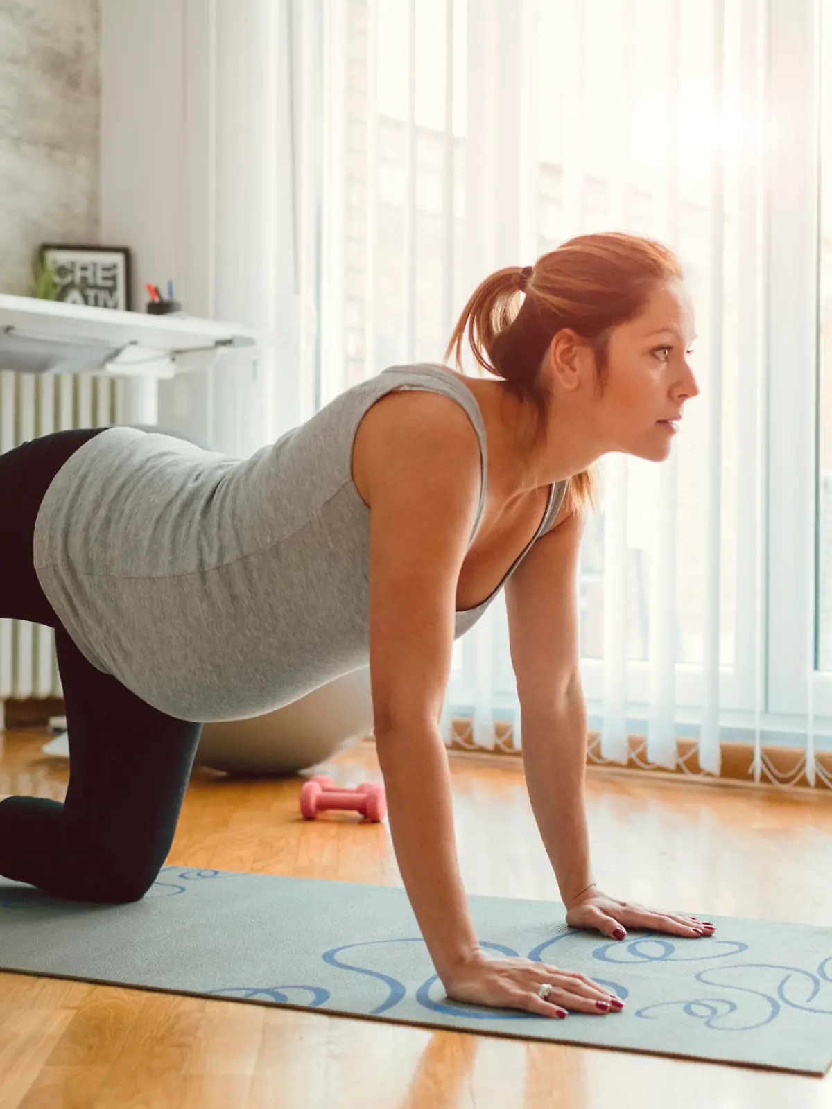 30 weeks pregnant woman exercising at home. Exercising on exercise mat and working stretching exercise.