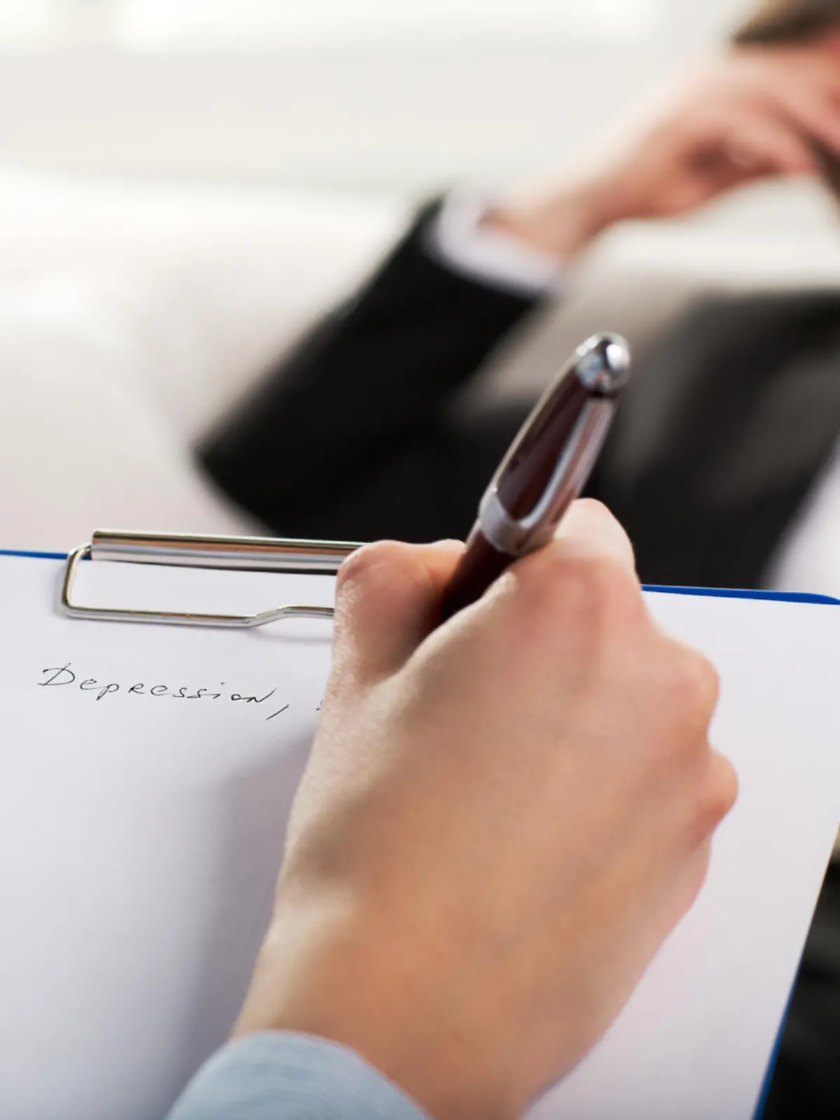 Over the shoulder view, of a business man sit on a couch talking to his psychiatrist