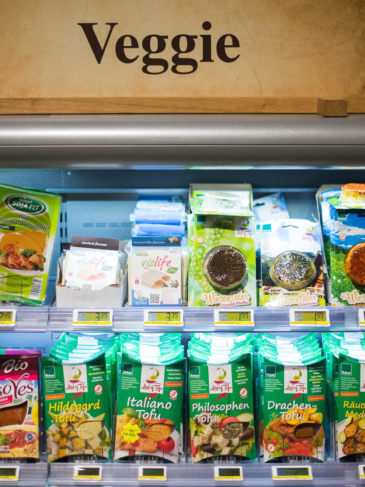 ARCHIV - Ein Schild «Veggie» steht am 11.05.2015 in Hamburg in einem Edeka-Markt auf einem Kühlregal mit vegetarischen Produkten. Vegetarische oder vegane Ernährungsweise liegt im Trend. Selbst bekannte Wursthersteller stocken ihr Produktportfolio mit Fleischersatz auf. Foto: Daniel Bockwoldt/dpa (zu lni "«Nur ein Revolutiönchen» - Fleischkonsum trotz Veggie-Trend konstant" vom 11.06.2015) +++(c) dpa - Bildfunk+++