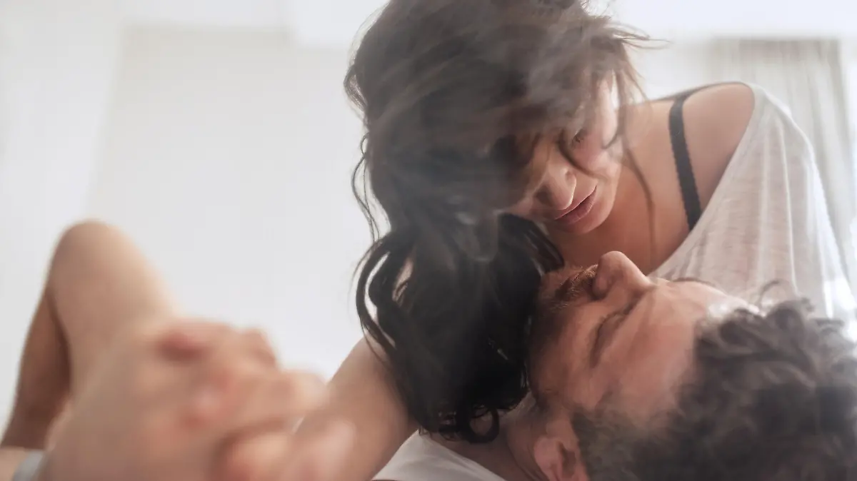 Intimate young couple in bedroom enjoying sensual foreplay. Man and woman lying on bed having.