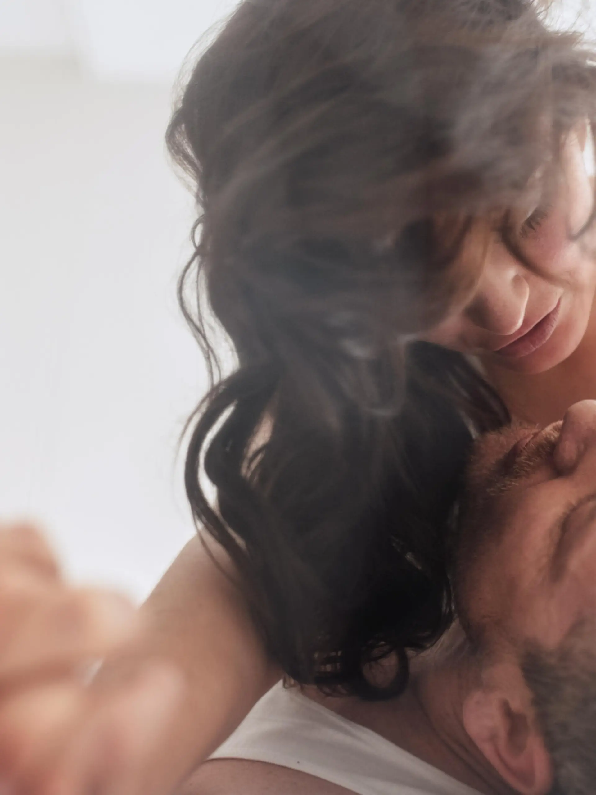 Intimate young couple in bedroom enjoying sensual foreplay. Man and woman lying on bed having.