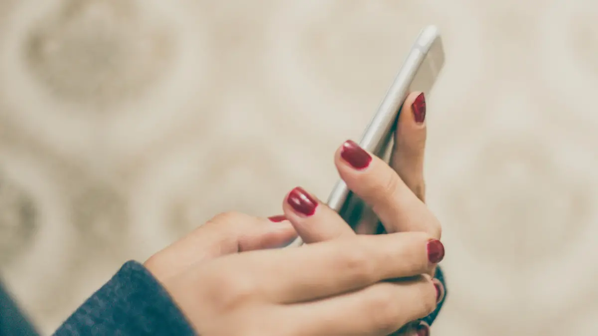 Woman hands holding smart phone on vintage background, close-up