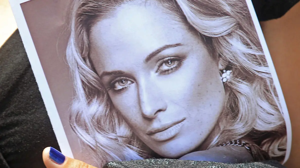 FILE - In this Tuesday, Feb. 19, 2013 file photo a mourner holds a funeral program with a portrait of Reeva Steenkamp, the late girlfriend of Oscar Pistorius, in Port Elizabeth, South Africa. (AP Photo/Schalk van Zuydam-file) |