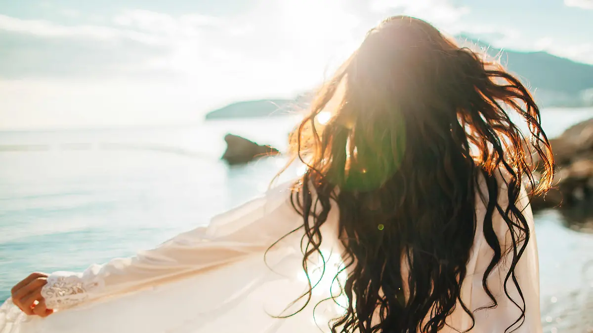 girl running dreamy with wind in hair and sunflare on beach sunset. defocus