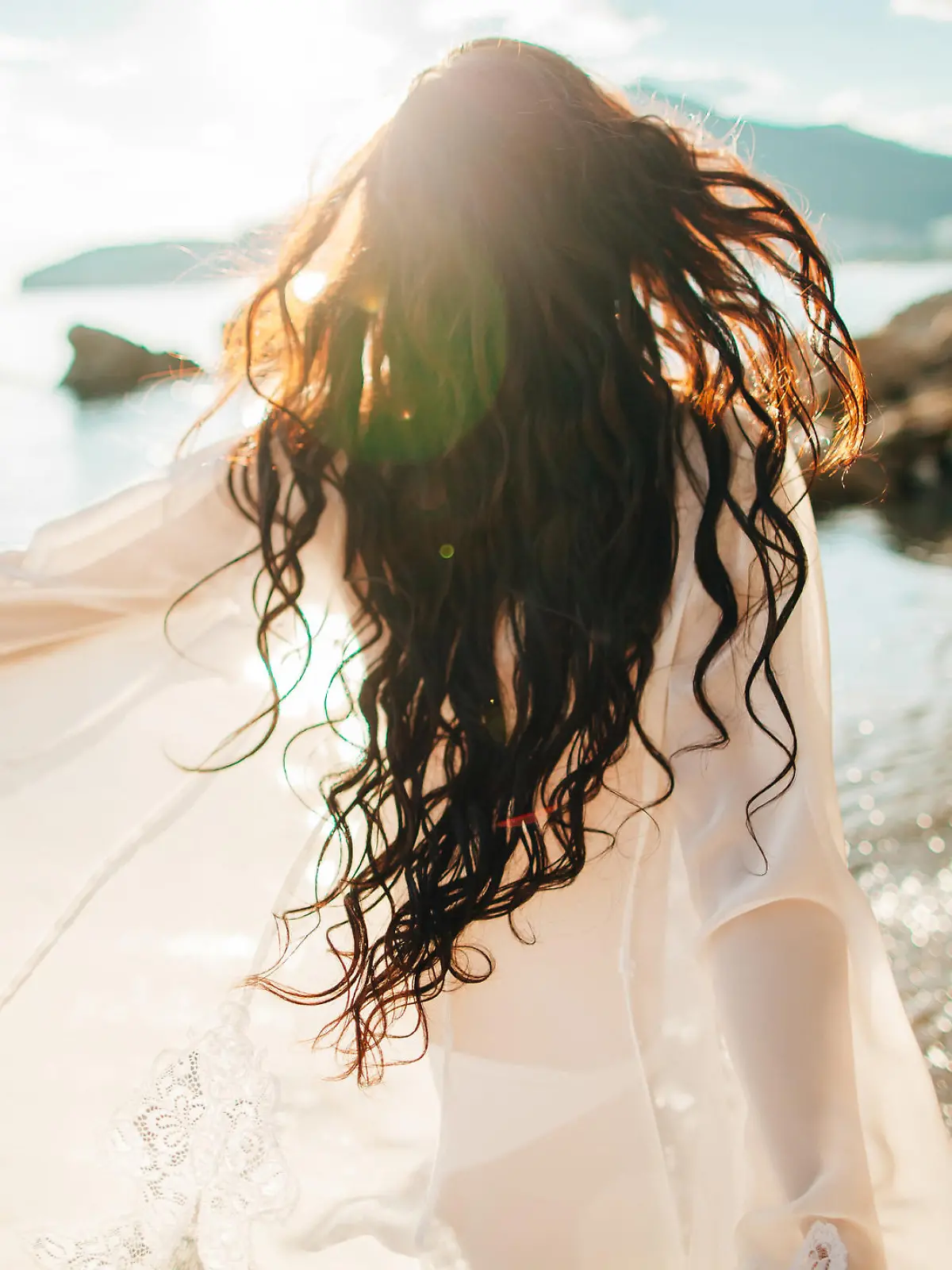 girl running dreamy with wind in hair and sunflare on beach sunset. defocus