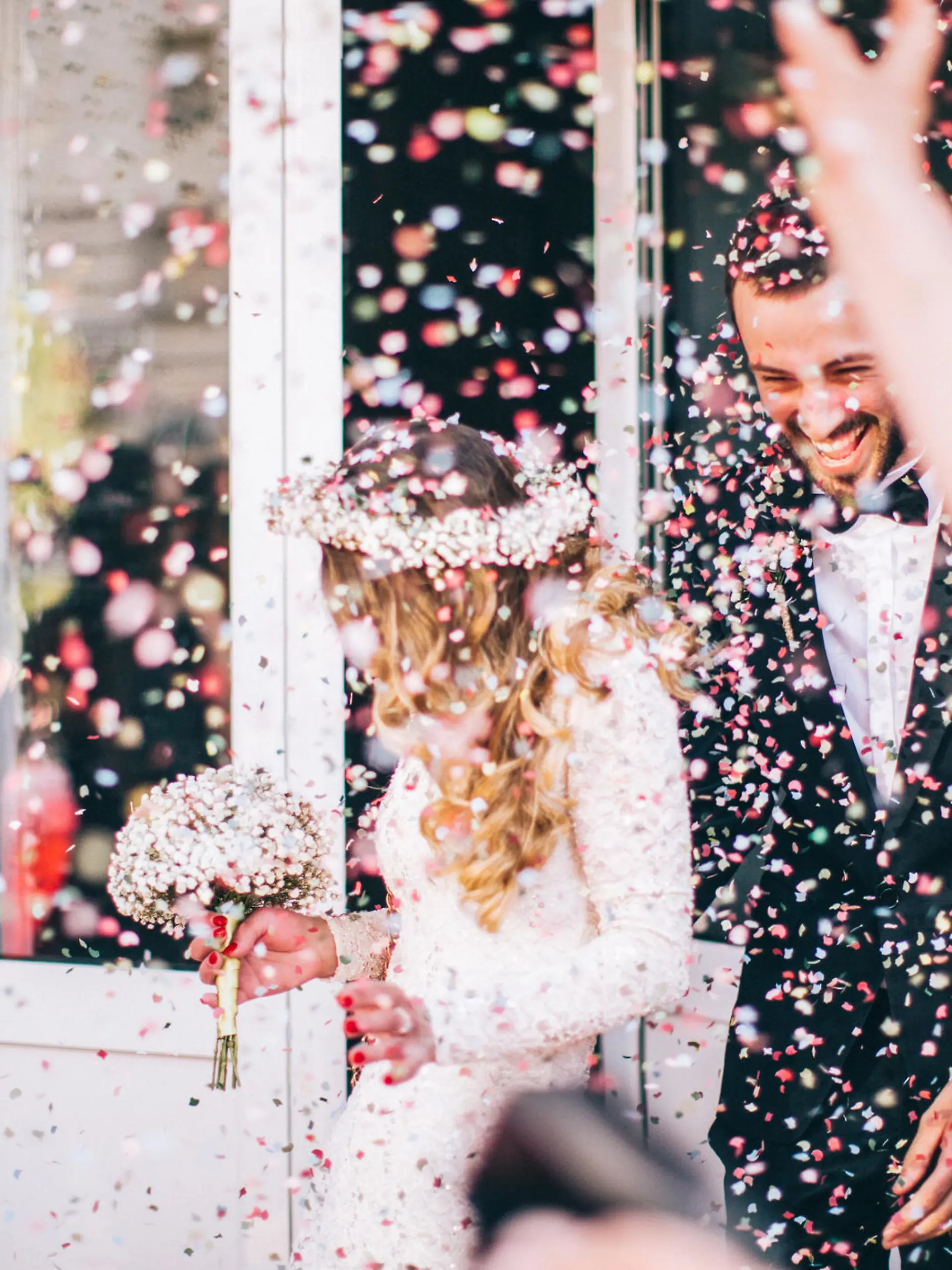 Photo of just married couple. Guests are throwing confetti in the air.