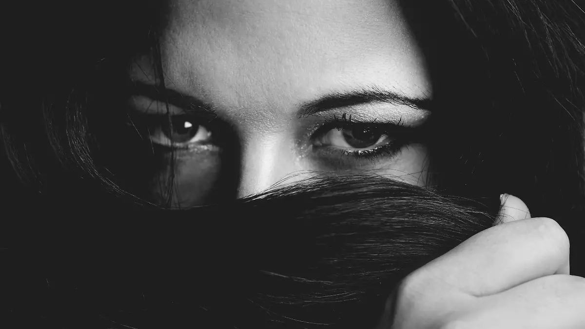 Cropped monochrome portrait of a beautiful young woman covering her mouth with her hair