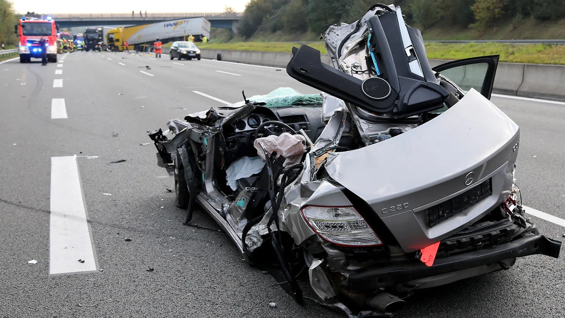 Ein verunglückter Pkw, der zuvor gegen den Lkw im Hintergrund geprallt war, steht am 19.10.2017 auf der Autobahn A3 bei Aschaffenburg (Bayern). Der Fahrer des Lastwagens hatte die Kontrolle über seinen Transporter verloren, die Betonbegrenzung zwischen den Fahrbahnen durchbrochen und war in den Gegenverkehr gefahren. Für den Fahrer des entgegenkommenden Wagens kam jede Hilfe zu spät. (zu dpa "Autofahrer stirbt bei Frontalkollision mit Lkw auf Autobahn" vom 19.10.2017) Foto: Ralf Hettler/dpa +++(c) dpa - Bildfunk+++