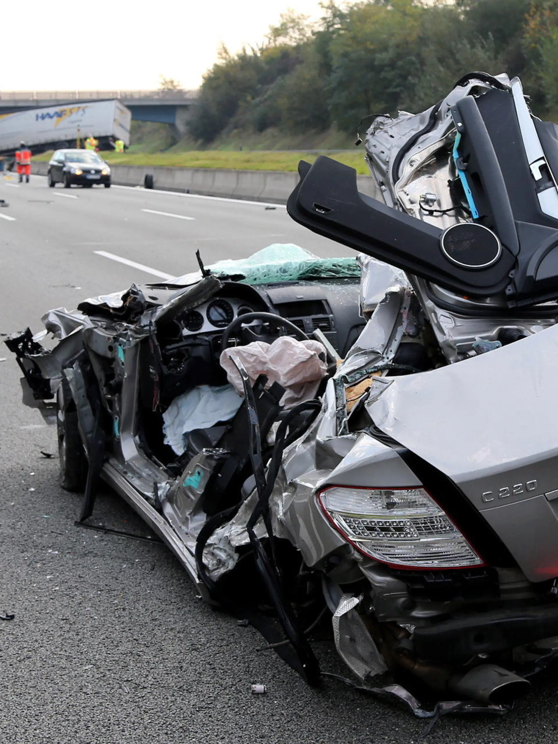 Ein verunglückter Pkw, der zuvor gegen den Lkw im Hintergrund geprallt war, steht am 19.10.2017 auf der Autobahn A3 bei Aschaffenburg (Bayern). Der Fahrer des Lastwagens hatte die Kontrolle über seinen Transporter verloren, die Betonbegrenzung zwischen den Fahrbahnen durchbrochen und war in den Gegenverkehr gefahren. Für den Fahrer des entgegenkommenden Wagens kam jede Hilfe zu spät. (zu dpa "Autofahrer stirbt bei Frontalkollision mit Lkw auf Autobahn" vom 19.10.2017) Foto: Ralf Hettler/dpa +++(c) dpa - Bildfunk+++