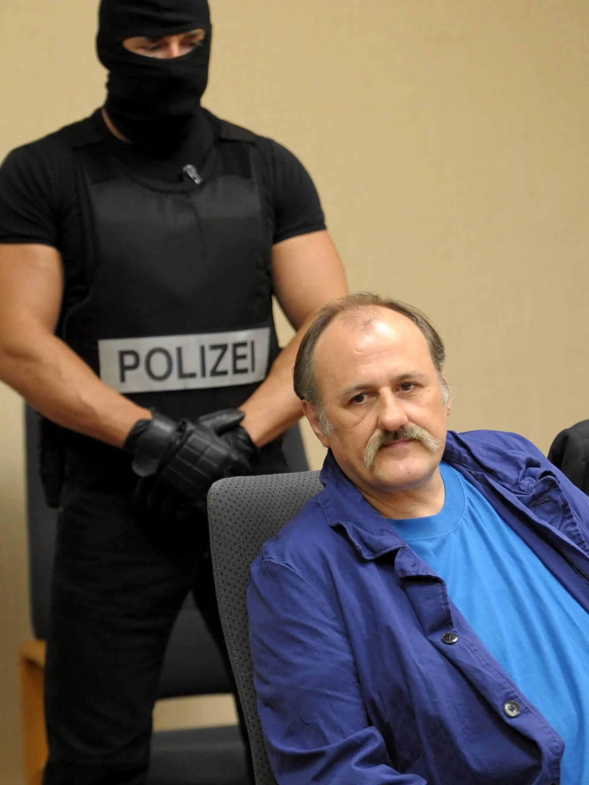 Der Gladbecker Geiselgangster Hans-Jürgen Rösner (r) sitzt am Dienstag (11.08.2009) im Amtsgericht in Bochum. Dahinter steht ein Beamter eines Spezialeinsatzkommandos. Rösner muss sich wegen Drogenhandels verantworten. Der 52-Jährige soll im Gefängnis dabei erwischt worden sein, wie er sieben Gramm Heroin portionierte. Rösner gilt als einer der bekanntesten Schwerverbrecher Deutschlands. Foto: Franz-Peter Tschauner dpa/lnw (zu lnw 7010 vom 11.08.2009) +++(c) dpa - Report+++