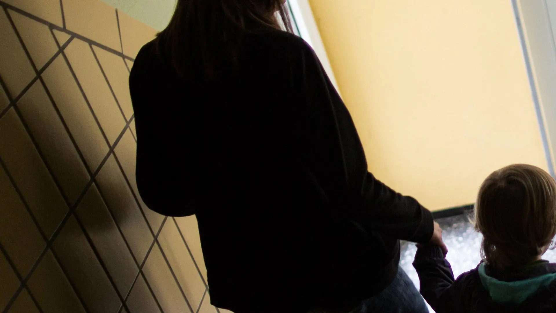 ARCHIV - Eine alleinerziehende Mutter geht am 01.07.2016 in Dortmund (Nordrhein-Westfalen) mit ihrem Sohn durch einen Hausflur die Treppe herunter. 1,6 Millionen Menschen im wohlhabenden Südwesten sind von Armut bedroht. (zu dpa «Armut im Reichtum - Alleinerziehende und Migranten mit hohem Risiko» vom 16.10.2017) Foto: Marcel Kusch/dpa +++(c) dpa - Bildfunk+++