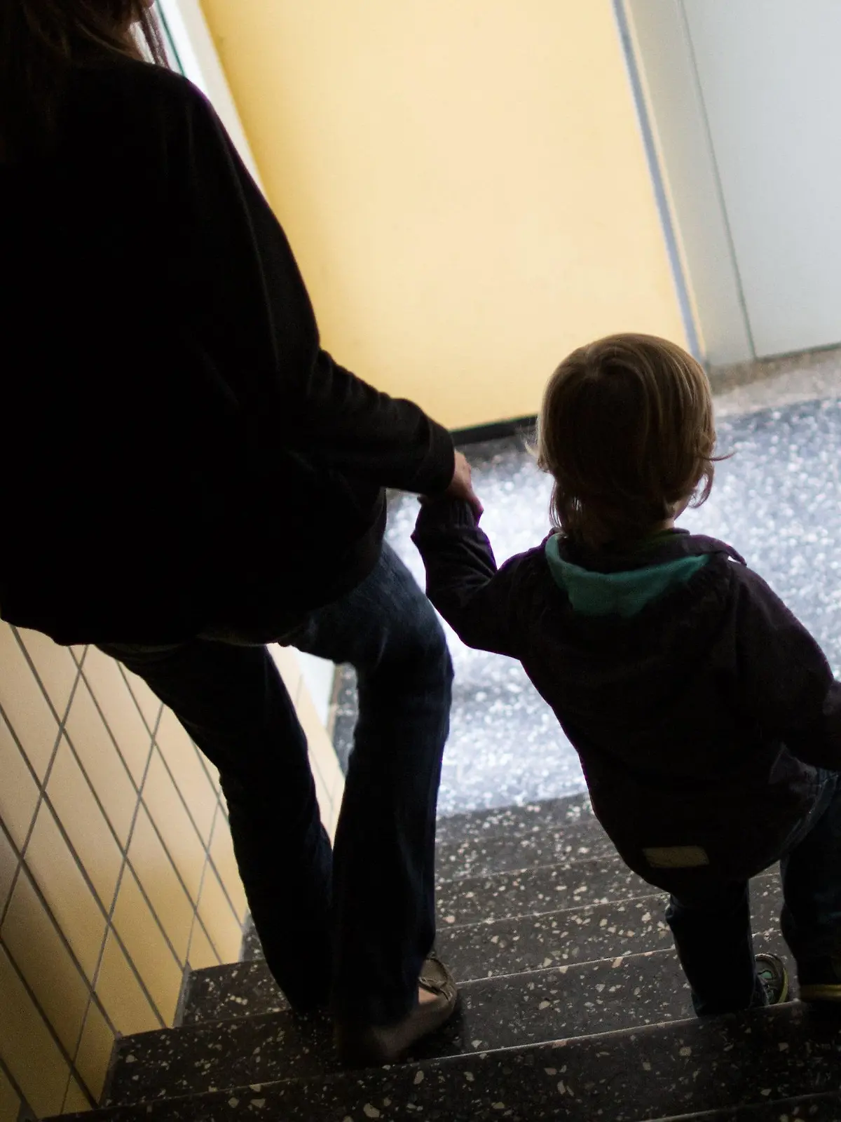 ARCHIV - Eine alleinerziehende Mutter geht am 01.07.2016 in Dortmund (Nordrhein-Westfalen) mit ihrem Sohn durch einen Hausflur die Treppe herunter. 1,6 Millionen Menschen im wohlhabenden Südwesten sind von Armut bedroht. (zu dpa «Armut im Reichtum - Alleinerziehende und Migranten mit hohem Risiko» vom 16.10.2017) Foto: Marcel Kusch/dpa +++(c) dpa - Bildfunk+++
