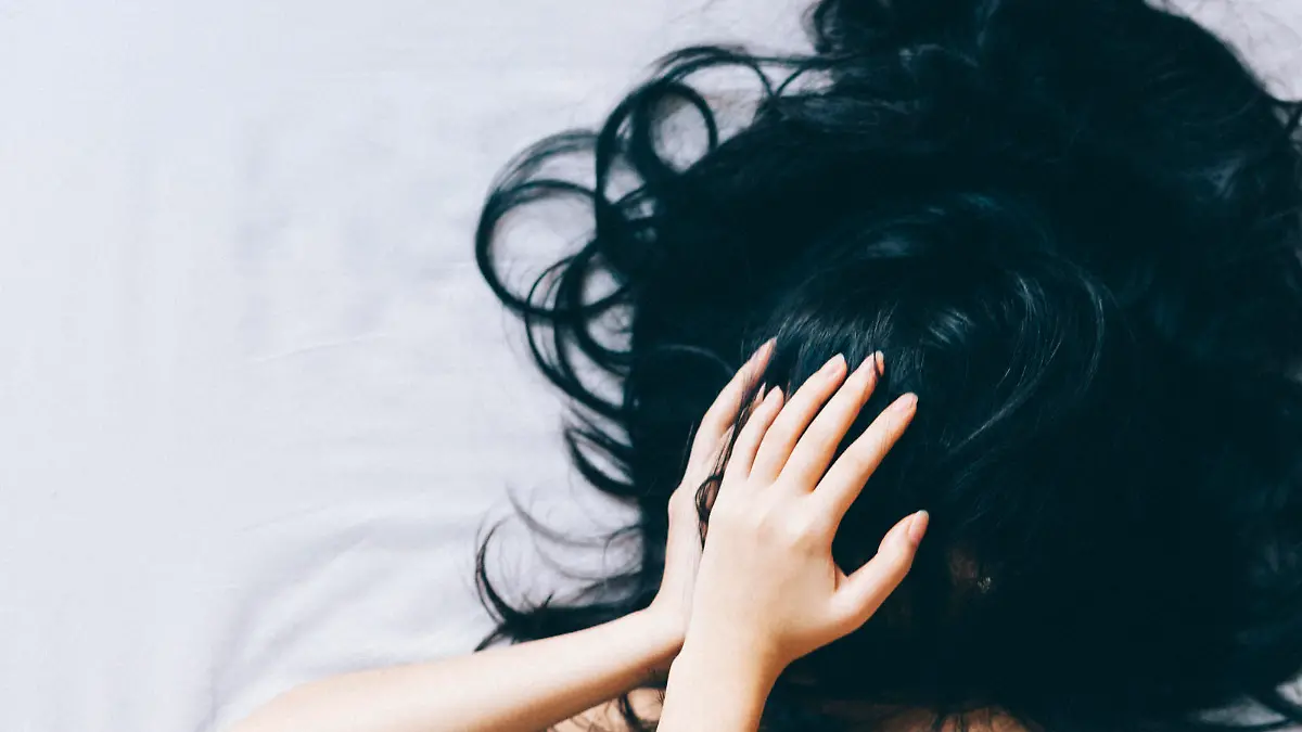 Young woman covering her face with hair and hands.