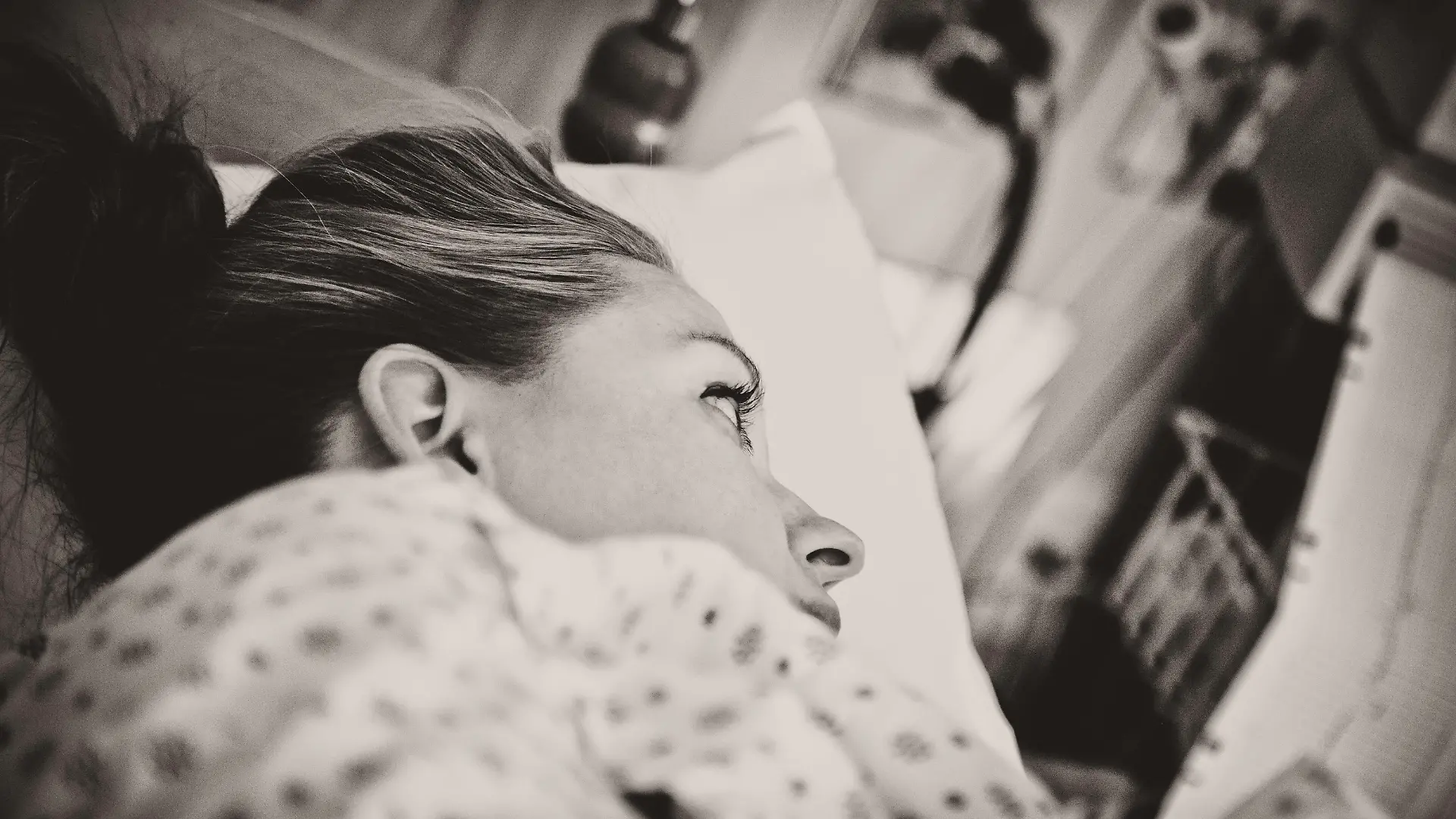 "Horizontal portrait of a young woman, laying in hospital bed in the labour and delivery ward, waiting to give birth to her child. Image is processed in a sepia tone and visible grain has been added. Image is processed from a 16 bit RAW file and profiled in ProPhoto RGB. All my images are professionally retouched.More from this series:"