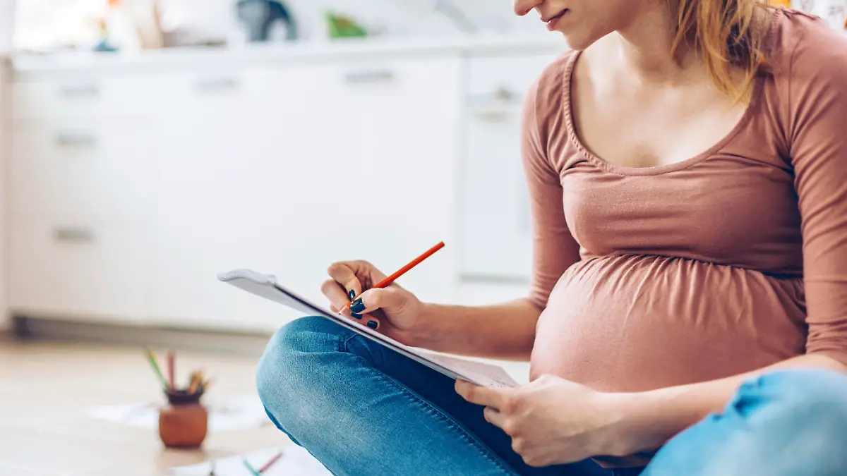 Pregnant woman at home relaxing by drawing with color pencils.