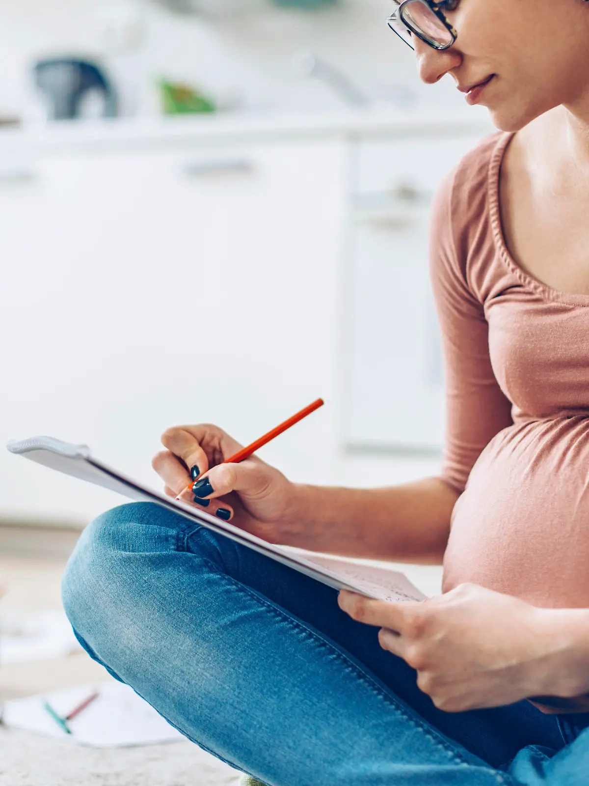 Pregnant woman at home relaxing by drawing with color pencils.