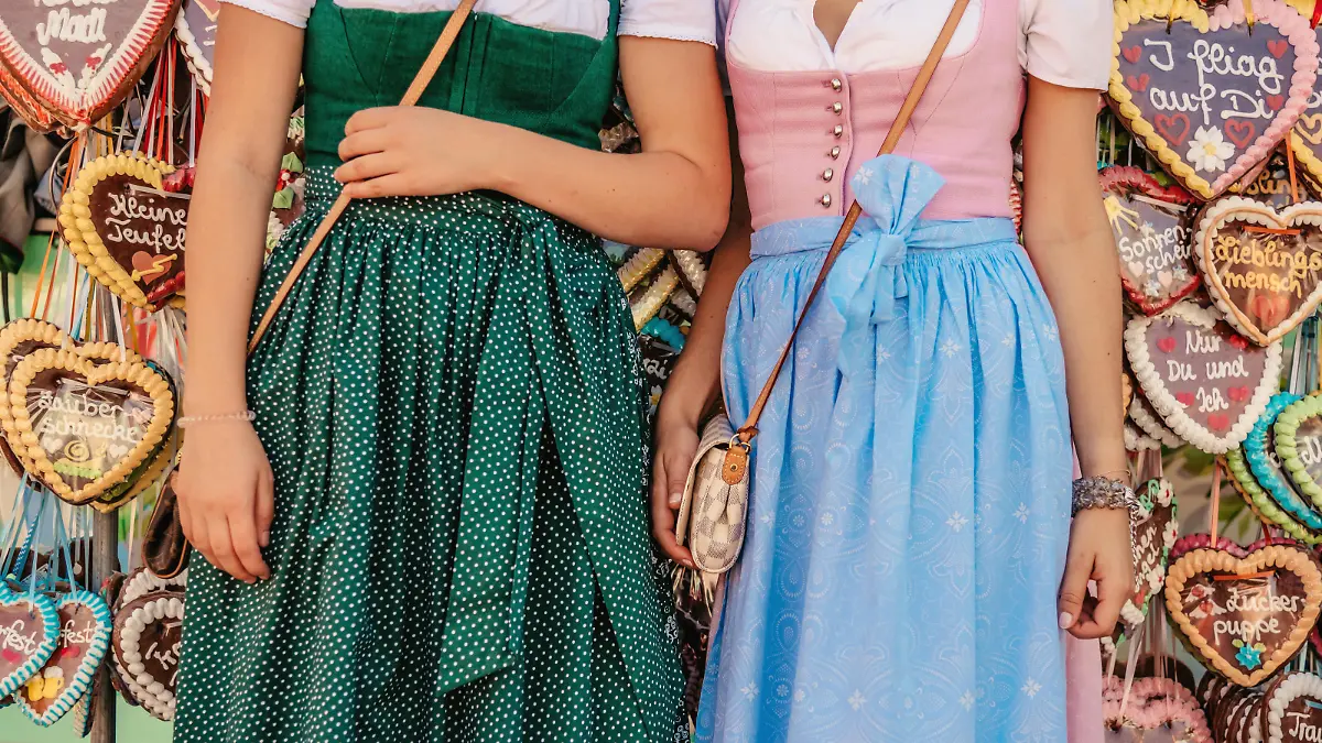 Munich, Germany - September 29, 2016: two young woman with traditional clothing in front of gingerbread hearts at Oktoberfest in Munich, focused on clothing, no faces visible
