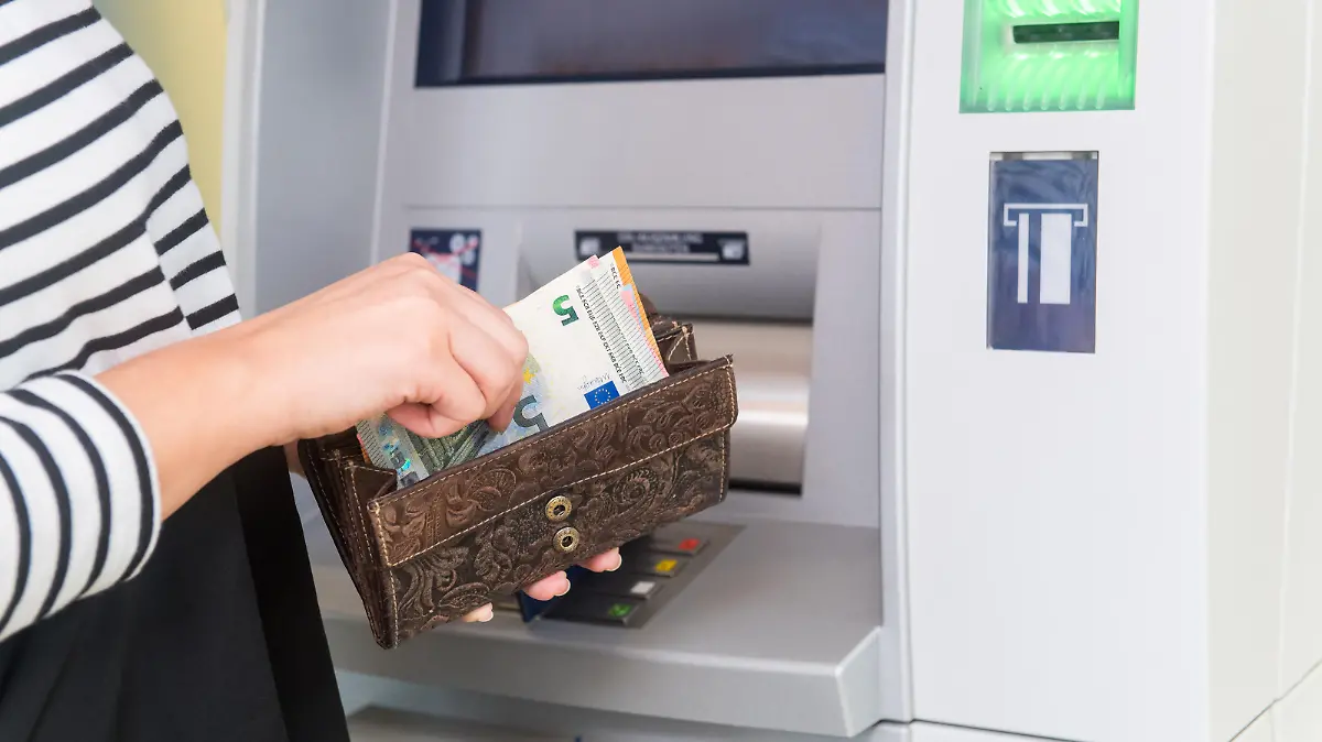 ILLUSTRATION - Eine Frau hebt am 04.04.2019 an einem Geldautomaten in Flensburg Geld ab (gestellte Szene). Foto: Benjamin Nolte