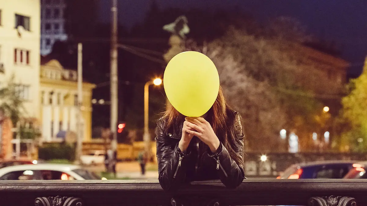 Young girl hiding her face behind a balloon