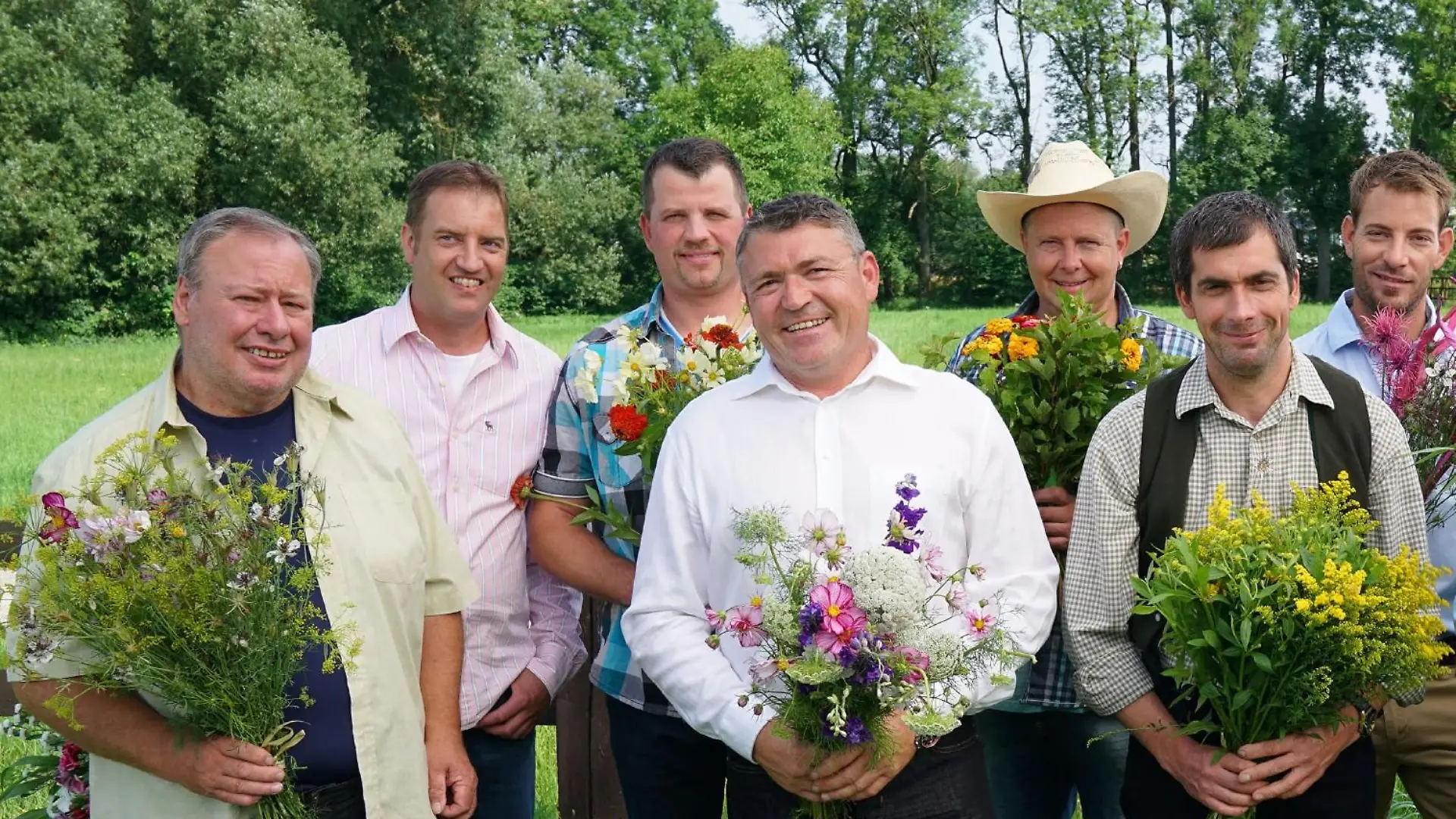 Gruppenfoto der Bauern während des Marketing-Drehs. V.l.: Reinhold, der einsame Hobbybauer, Bernhard "Benny", der treue Traktorfan, Michael "Micha", der bodenständige Brandenburger, Lothar, der ehrliche Eifler,  Herbert, der fleißige Pferdekutscher, Uwe, der waschechte Westerwälder, Gerald, der attraktive Farme,  Klaus, der herzliche Hesse,  Klaus Jürgen, der sympathische Milchviehhalter, Anton, der bayrische Bio-Bauer und Günter, der liebevolle Thüringer