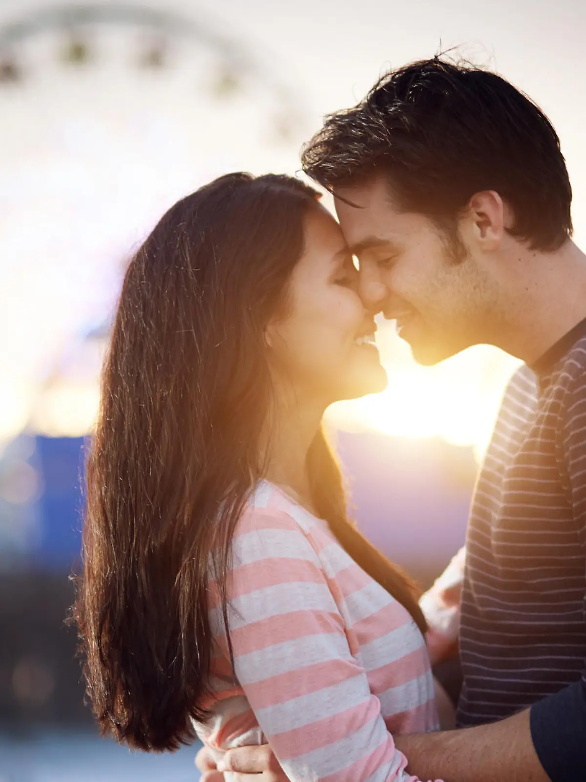 romantic couple in front of santa monica amusement park at sunset.
