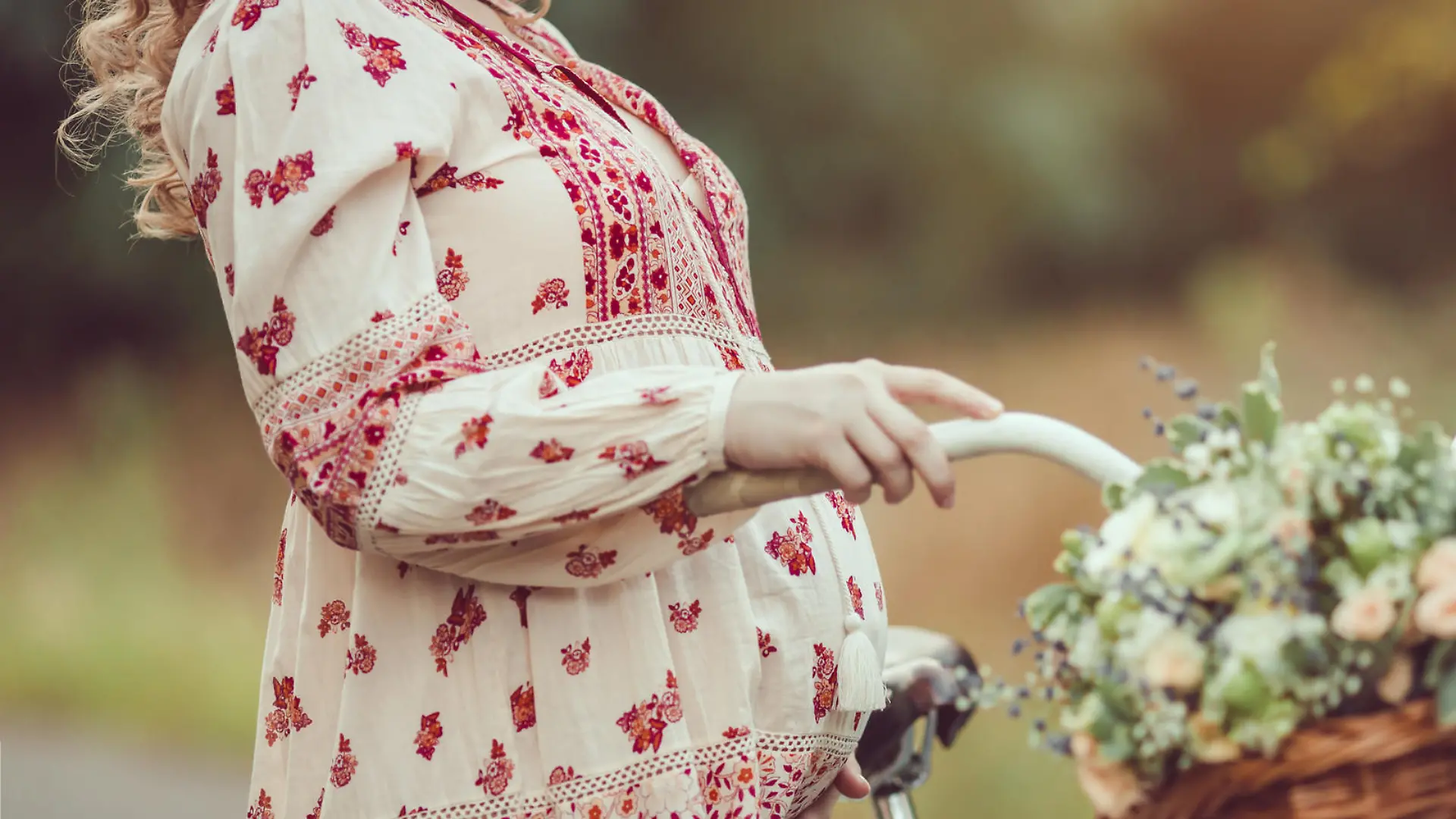 Pregnant belly against nature close-up. Pregnant girl retro French style with bicycle on a forest road. Beautiful pregnancy concept. Blonde happy woman with curly hair on nature background.