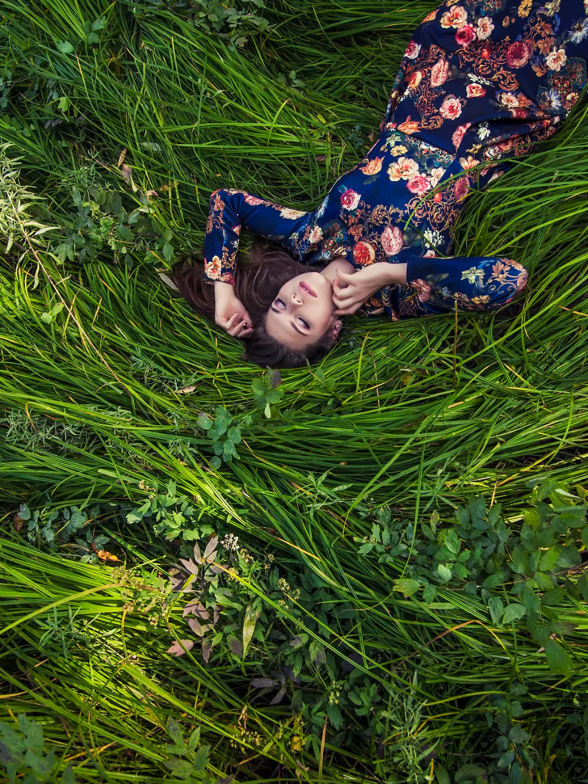 Beautiful young woman in dress lying in the grass in nature