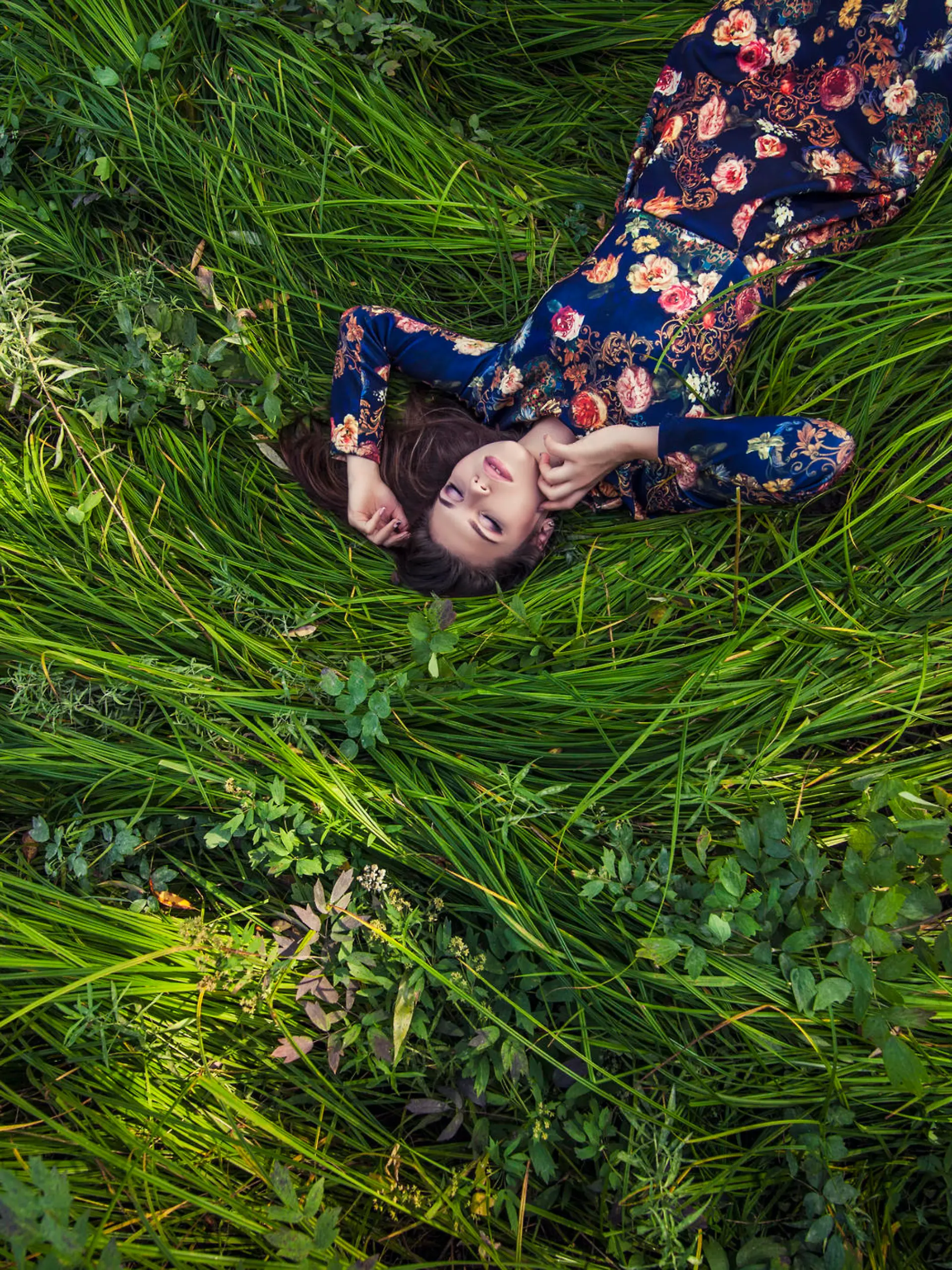 Beautiful young woman in dress lying in the grass in nature