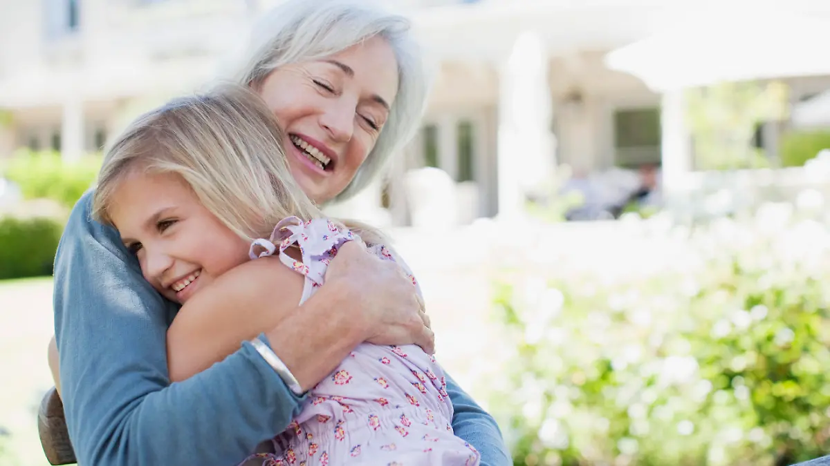 Grandmother and granddaughter hugging in backyard