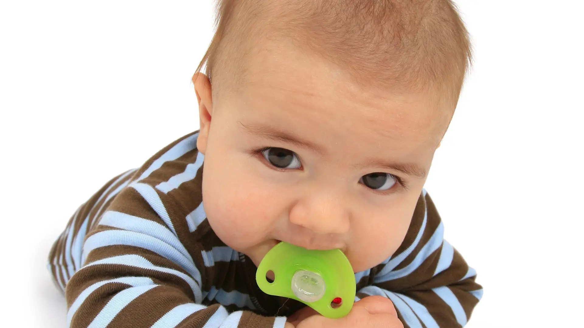 Baby mit Schnuller auf dem Bauch liegend