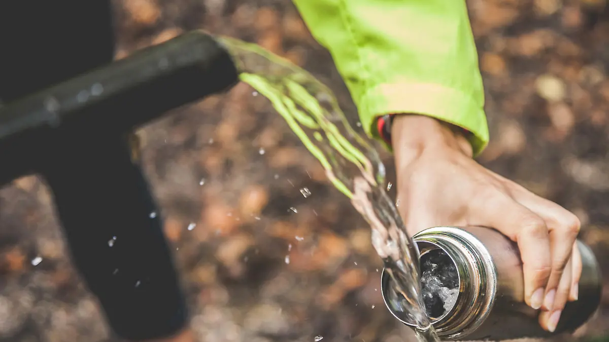 One woman refill water bottle from a source of water in mountain.