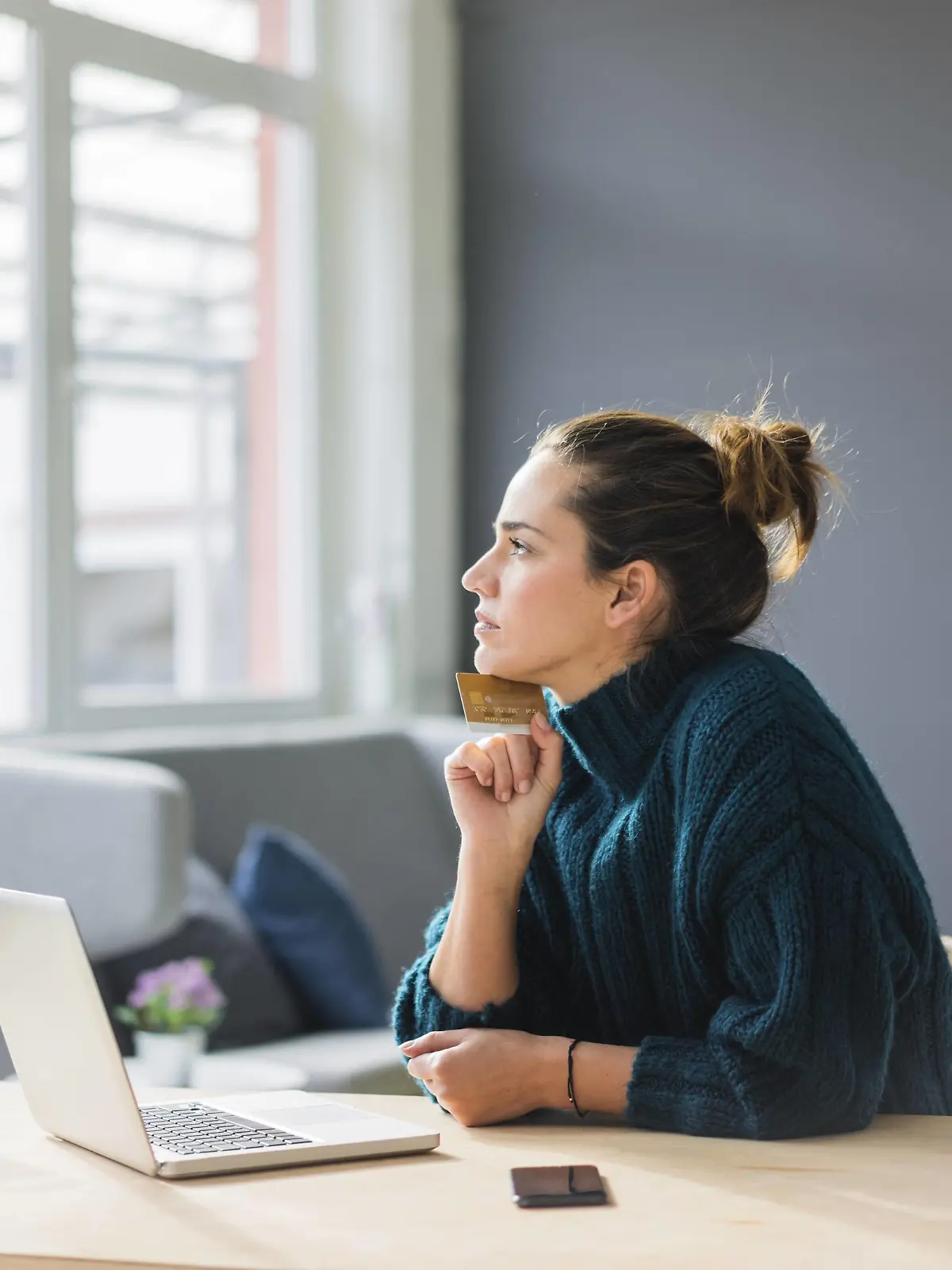  Profile of pensive woman with laptop and credit card sitting at desk at home looking out of window model released Symbolfoto property released PUBLICATIONxINxGERxSUIxAUTxHUNxONLY MOEF01854