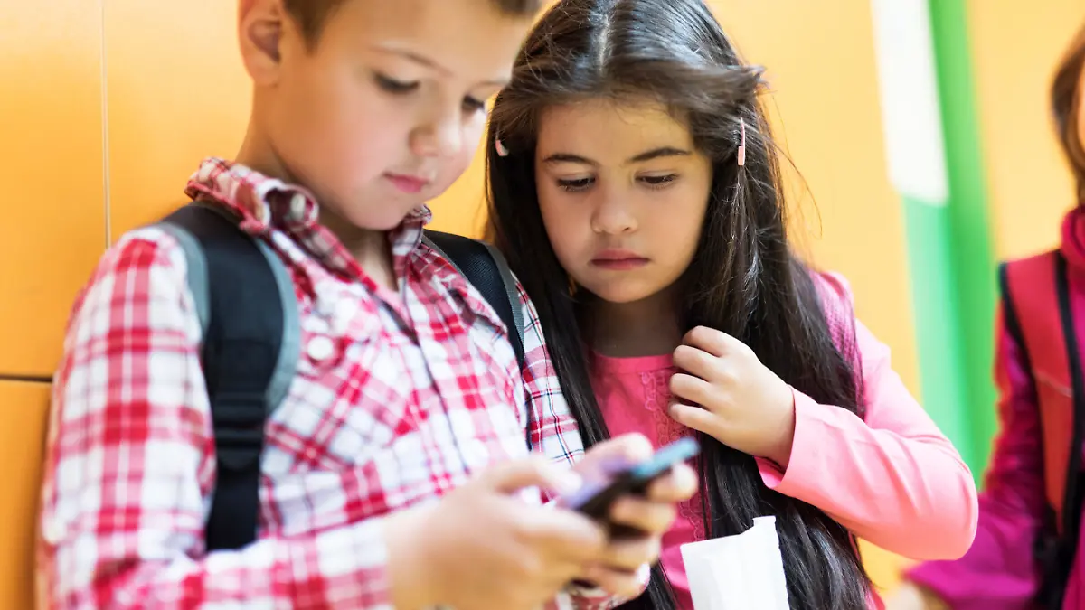 Two little children looking at cell phone.
