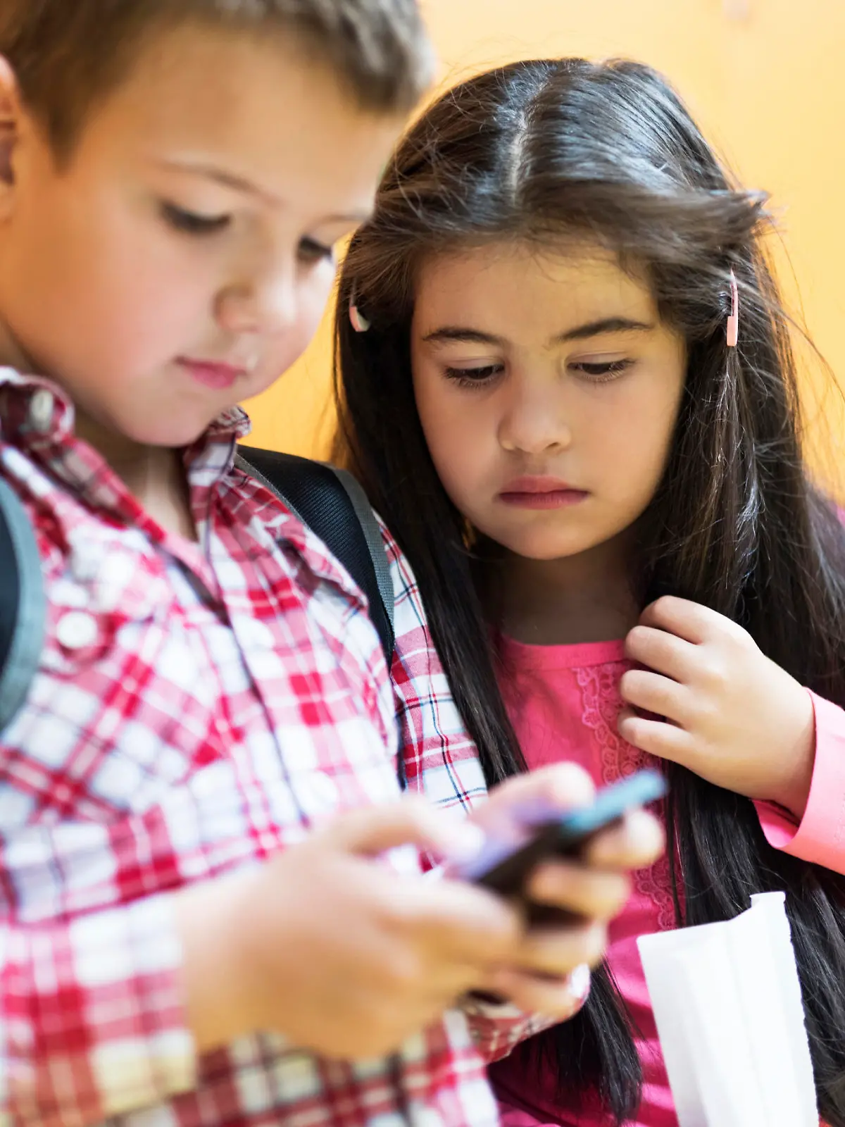 Two little children looking at cell phone.