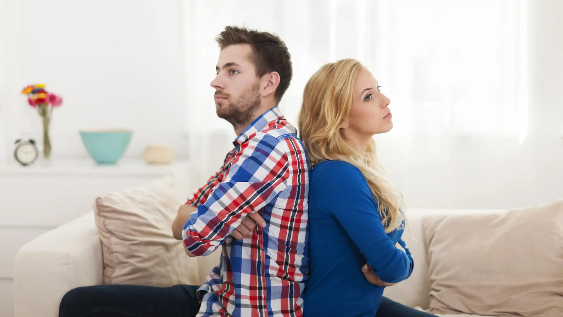 Angry young couple sitting back to back at home
