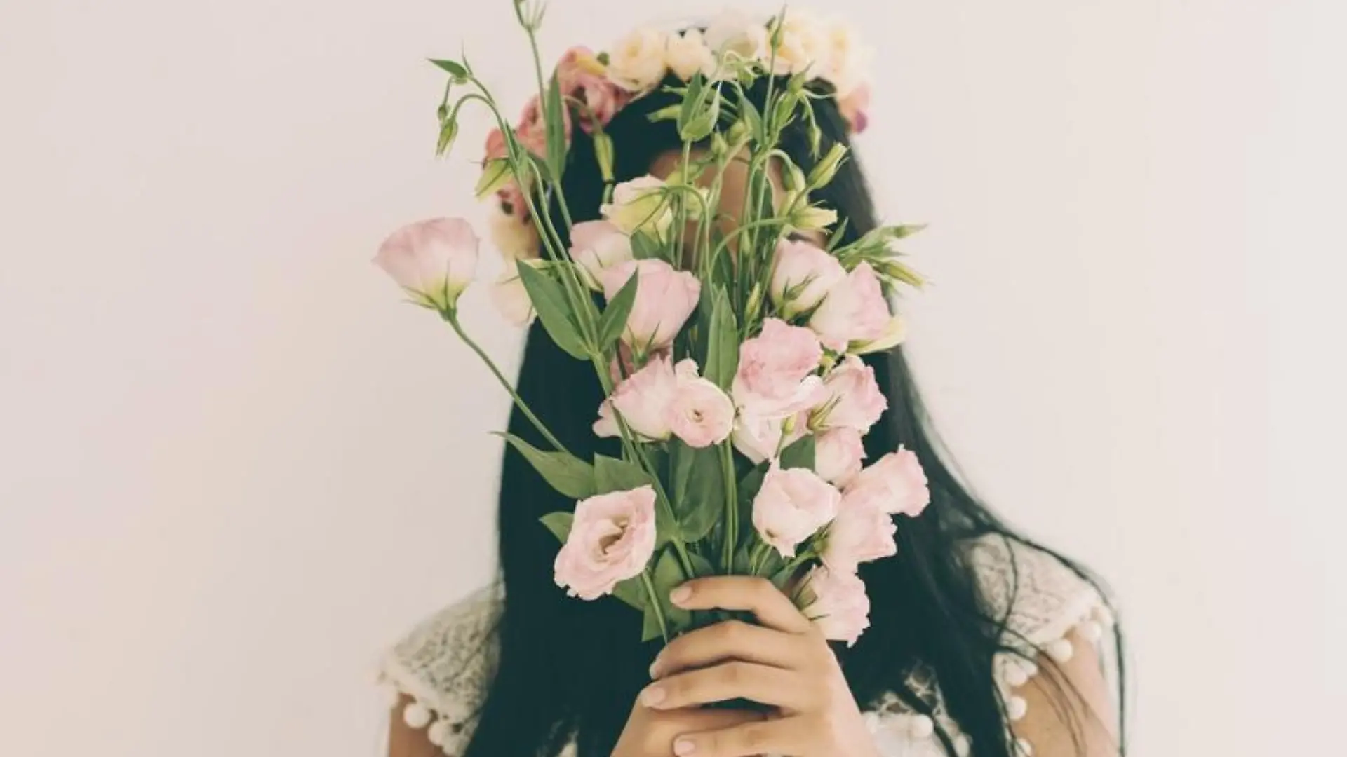 Woman holding pink flowers and hiding behind it